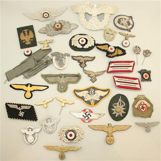 A collection of various German Third Reich cap badges, cloth badges and pins